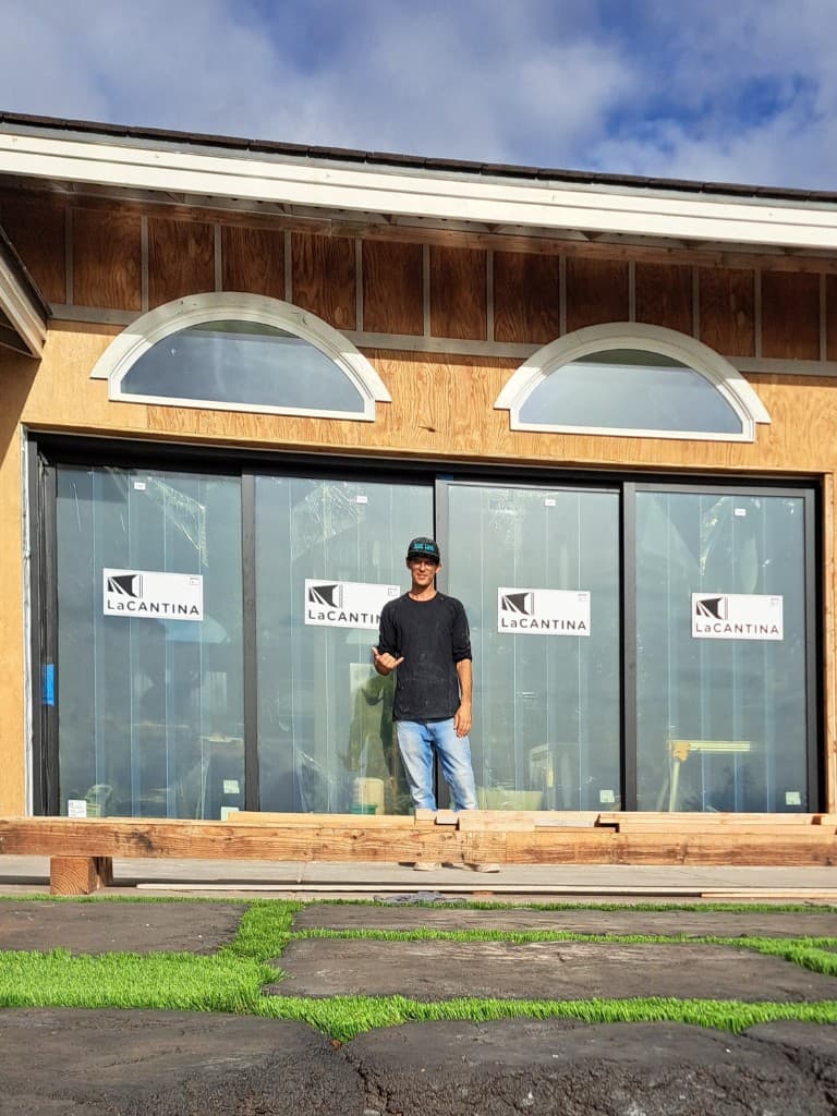 Aaron in front of a project with large sliding glass doors and custom windows