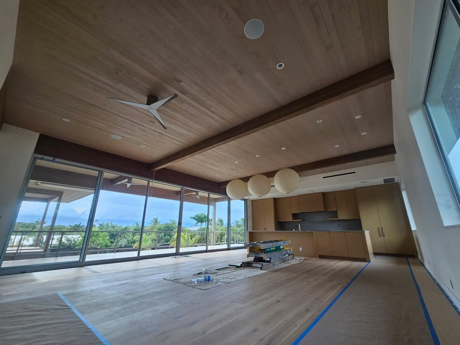 Open living area with a wood plank ceiling, exposed beam, oak floors and custom kitchen cabinets
