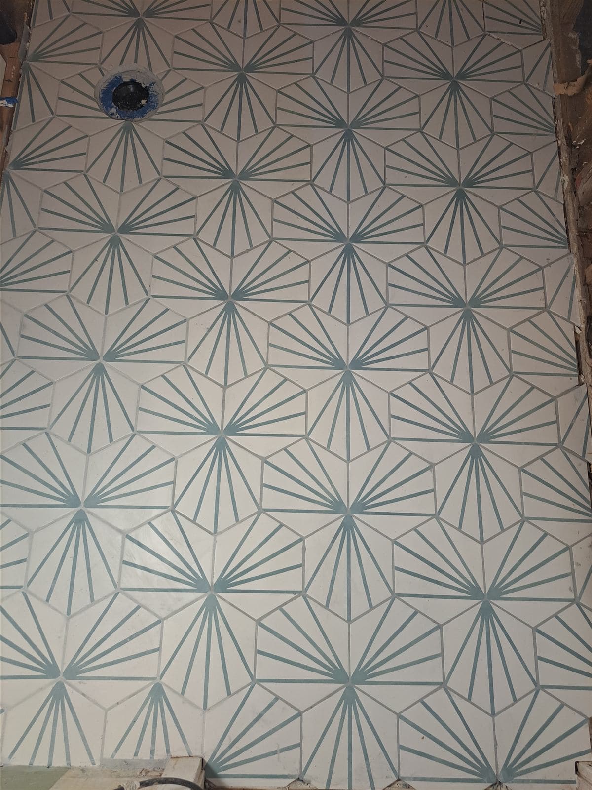 Finished floor of white hexagon tile with a teal starburst pattern